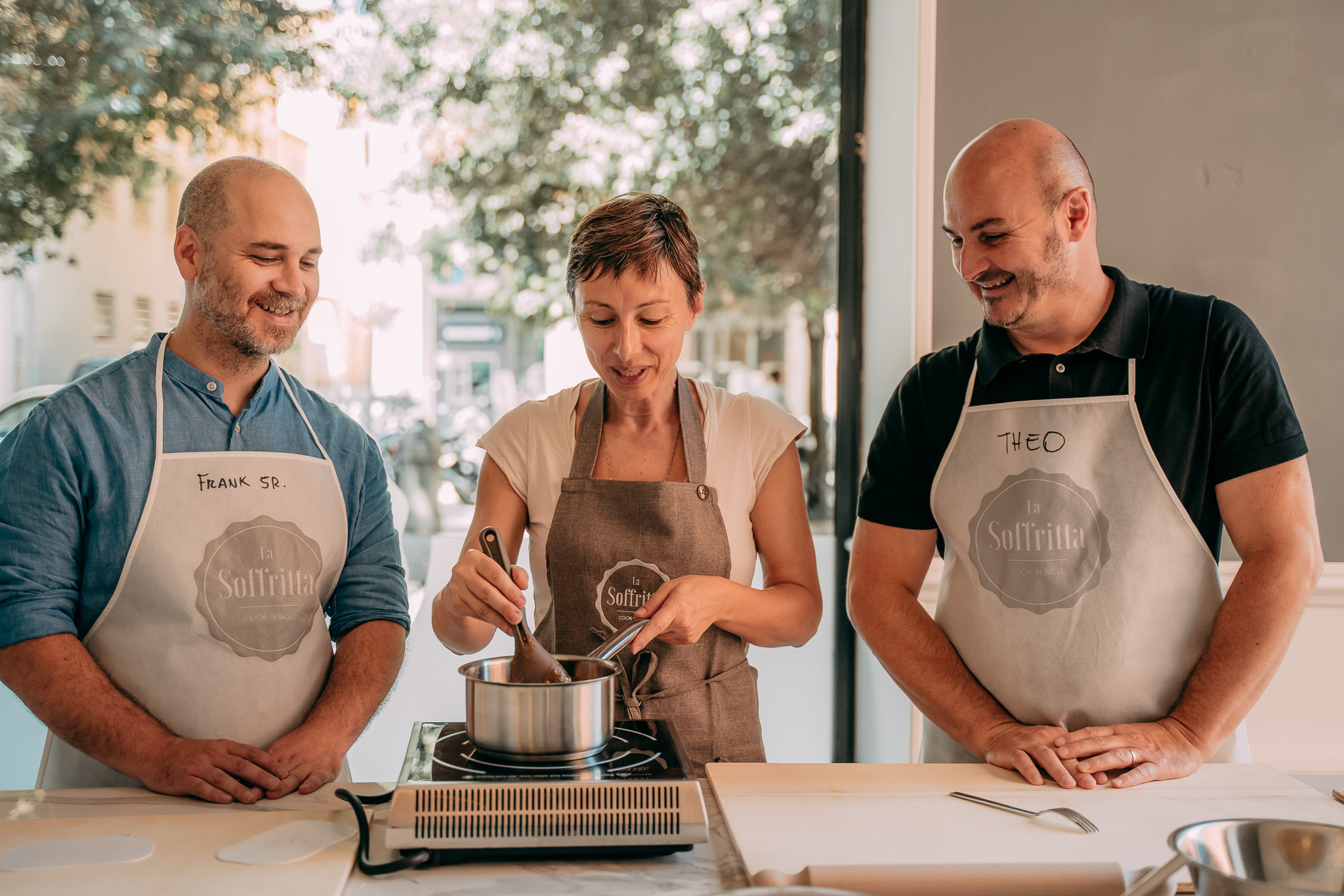 Chef e due partecipanti cucinano insieme ai fornelli de La Soffritta