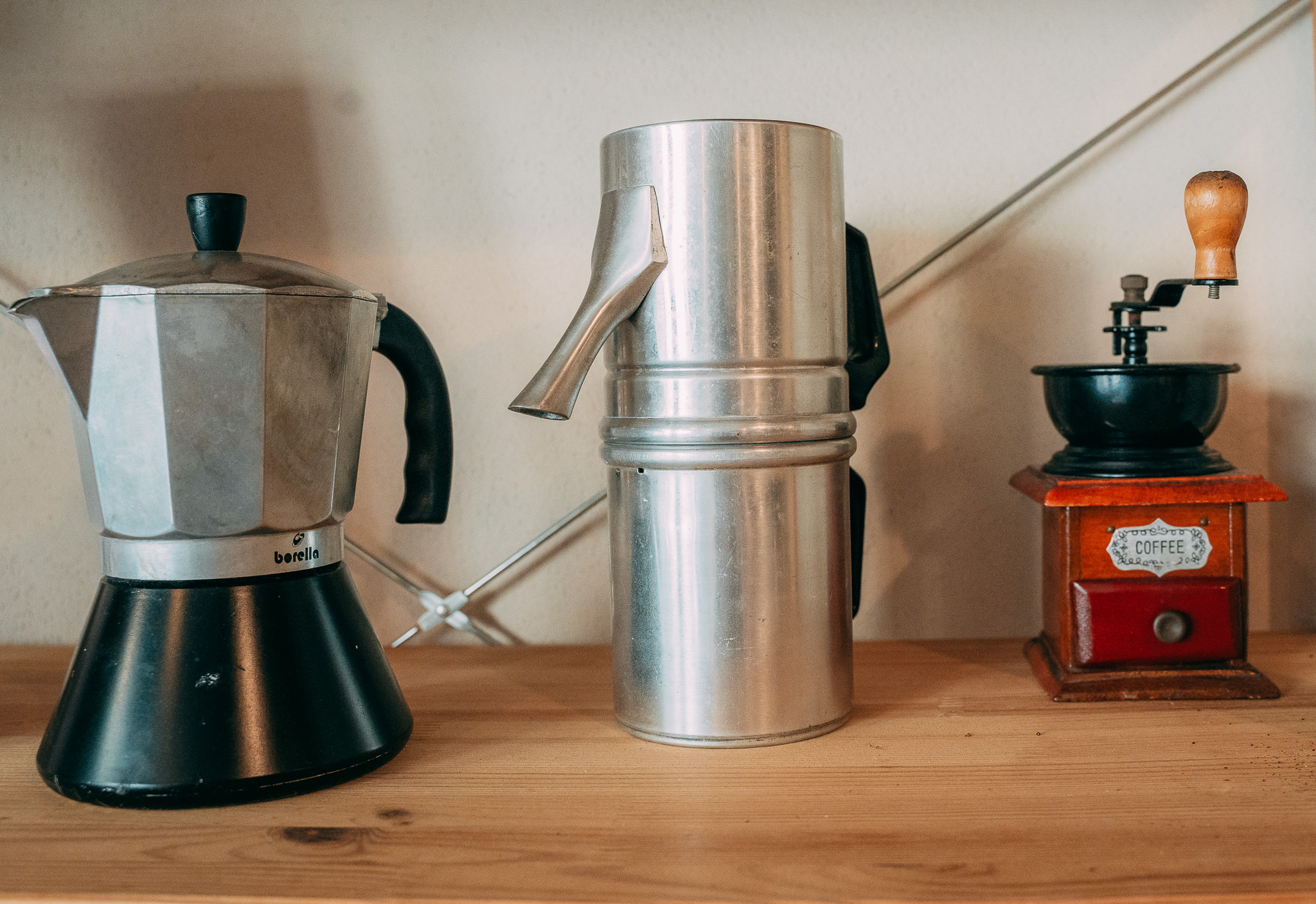 Moka, caffettiera e macinino su una mensola di legno