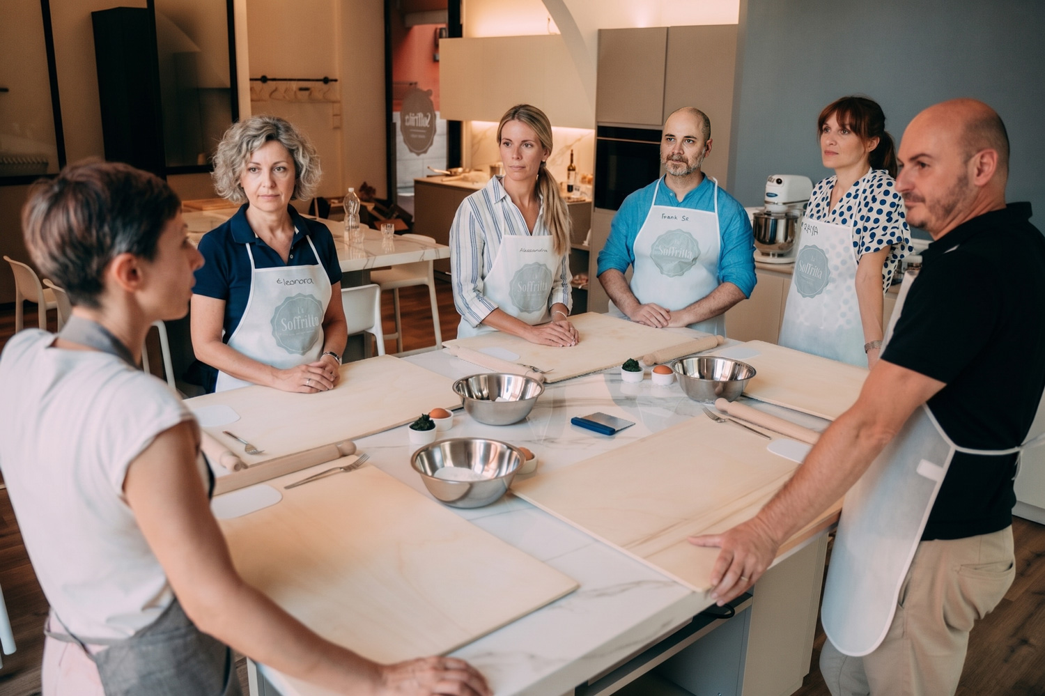 Gruppo di persone riunite al tavolo ascolta la spiegazione della chef