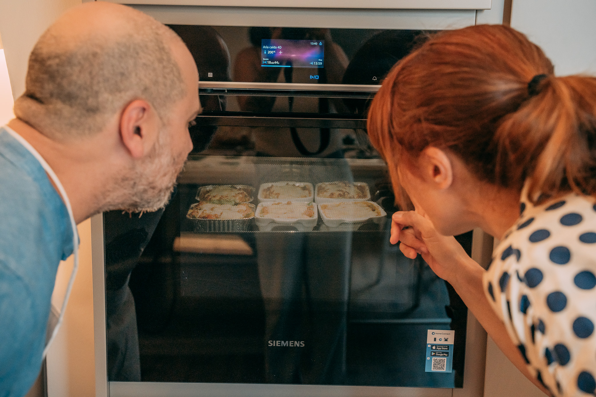 Due partecipanti guardano le lasagne cuocersi nel forno