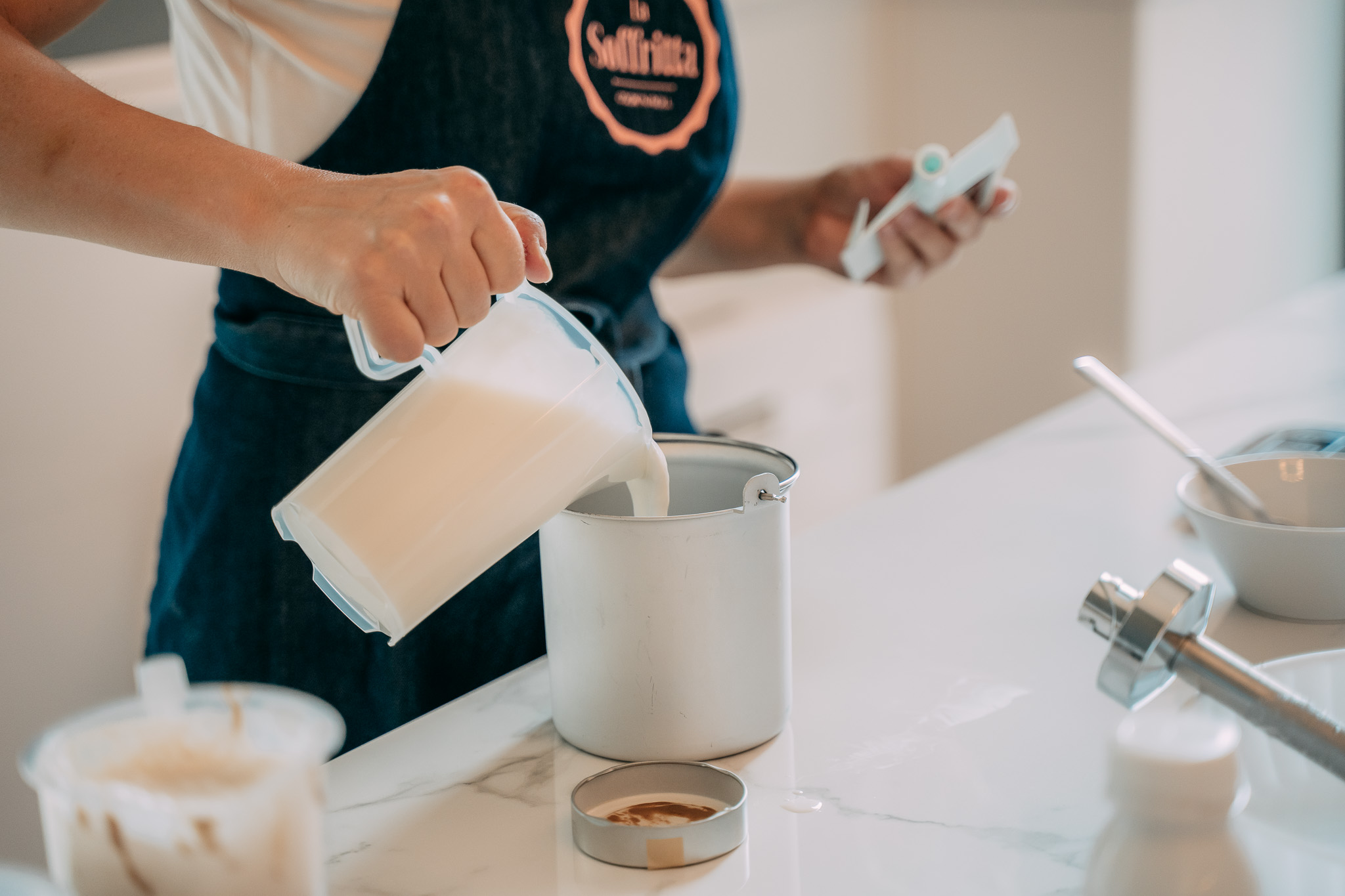 Mano versa il latte in un contenitore durante la preparazione del gelato artigianale