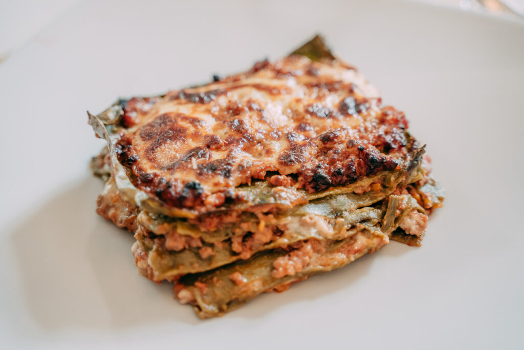 Fetta di lasagna al ragù con besciamella servita su un piatto da portata
