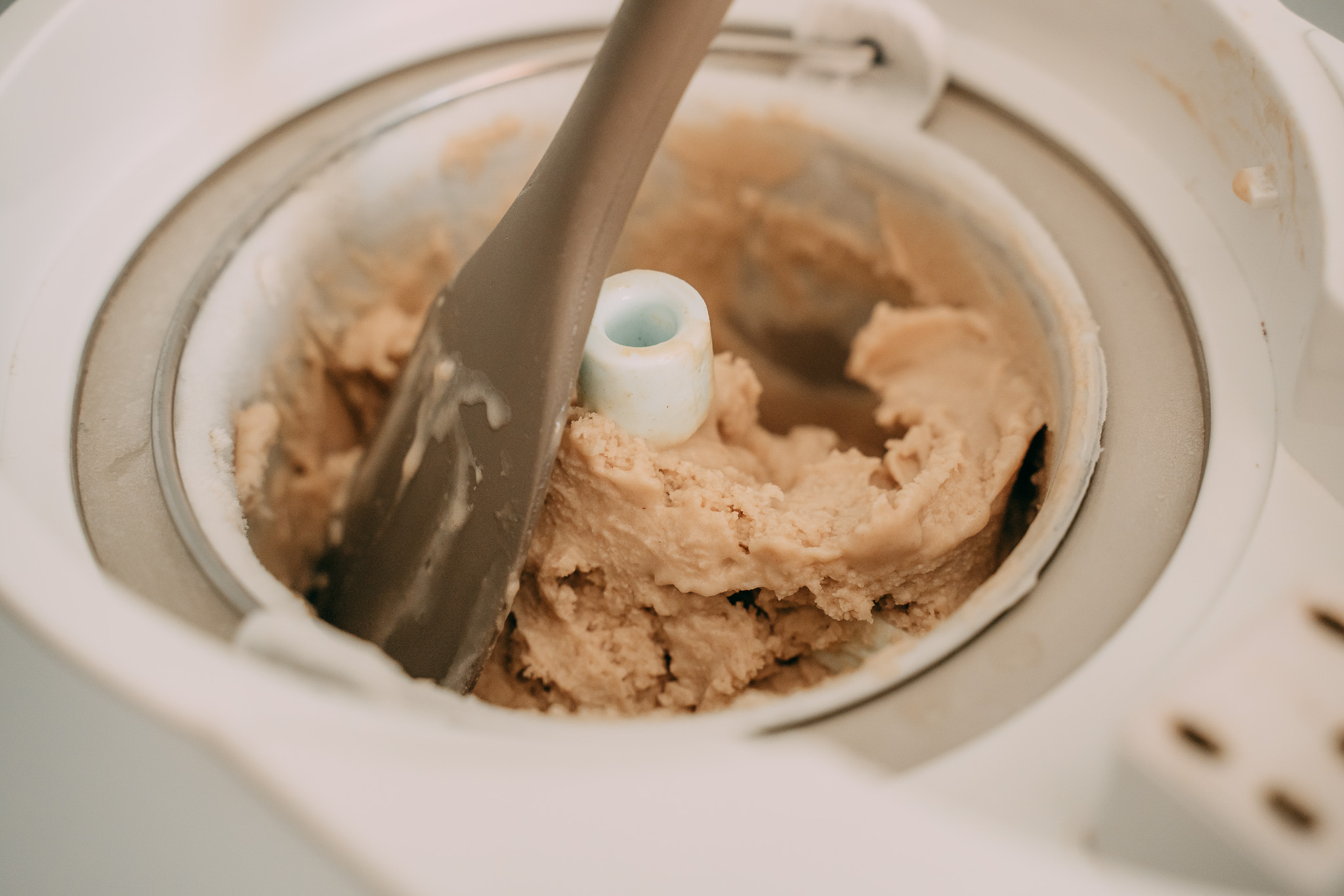 Gelatiera in funzione con gelato cremoso durante la preparazione artigianale del gelato