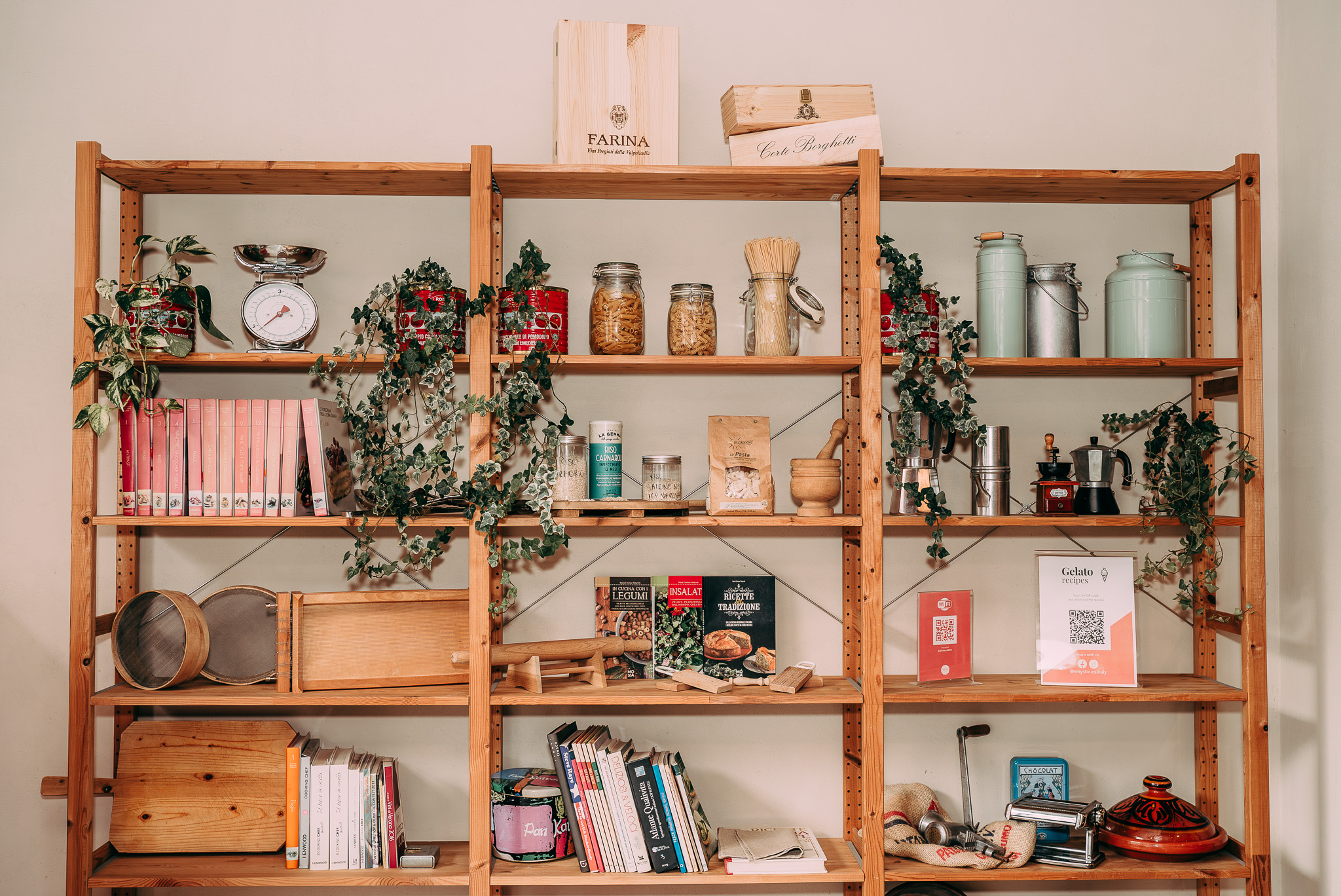 Libreria di legno de La Soffritta di Verona con ricettari, strumenti e ingredienti