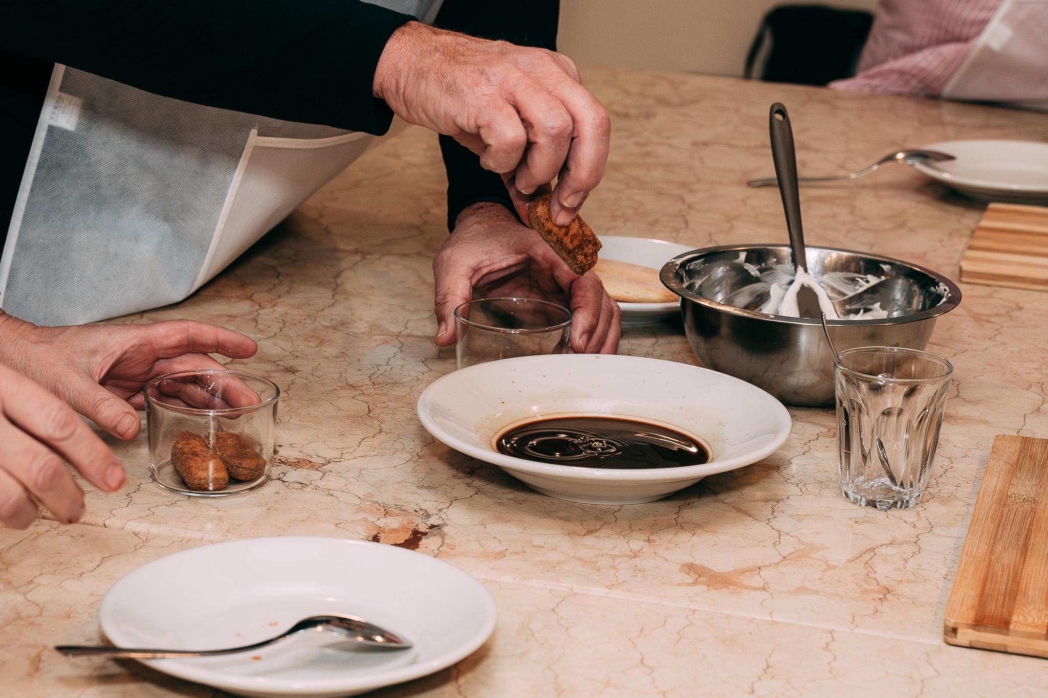 Mano che bagna un savoiardo nel caffè per la preparazione del tiramisù