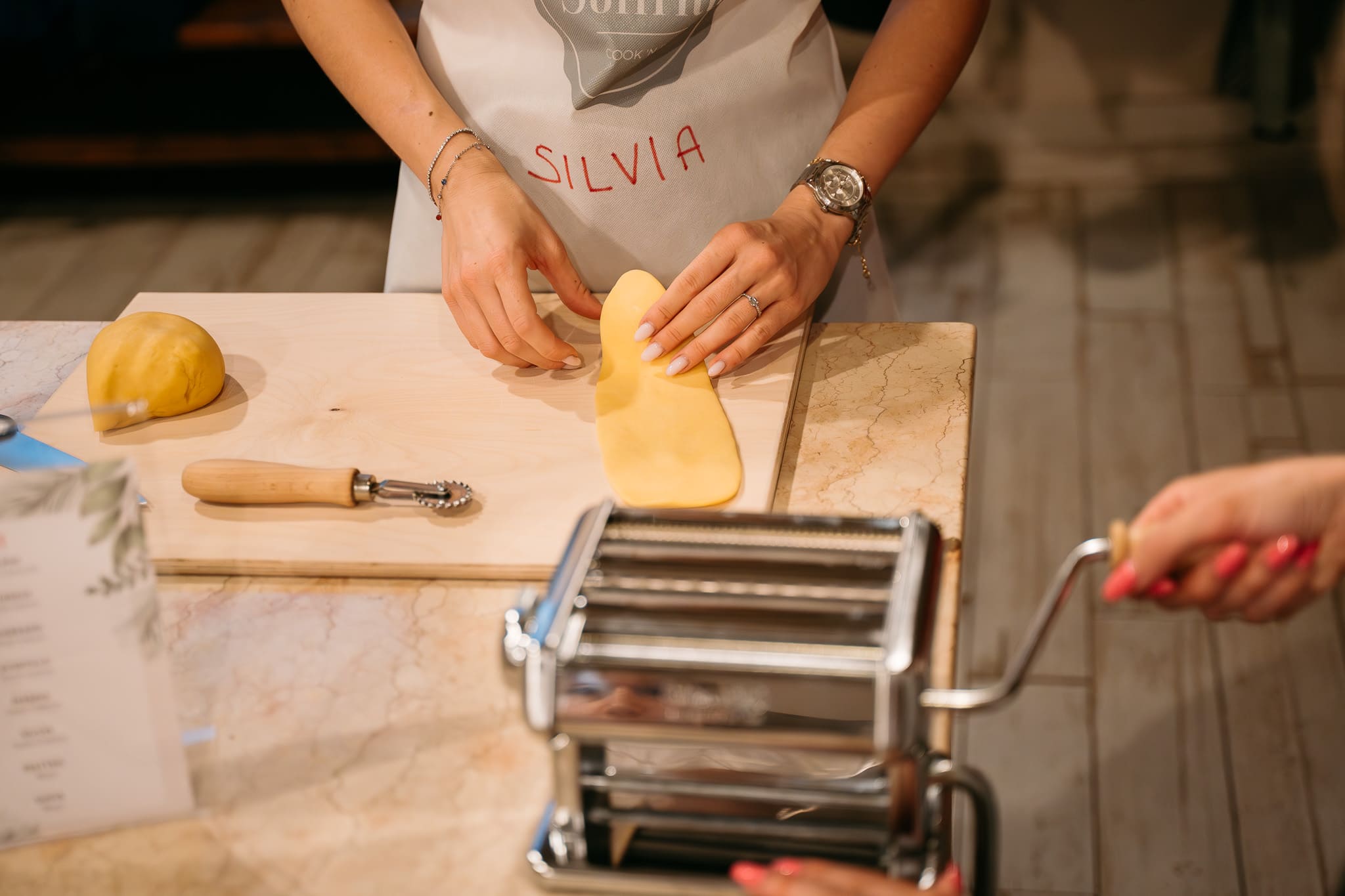 Mani stendono la pasta con la macchina per la pasta fresca