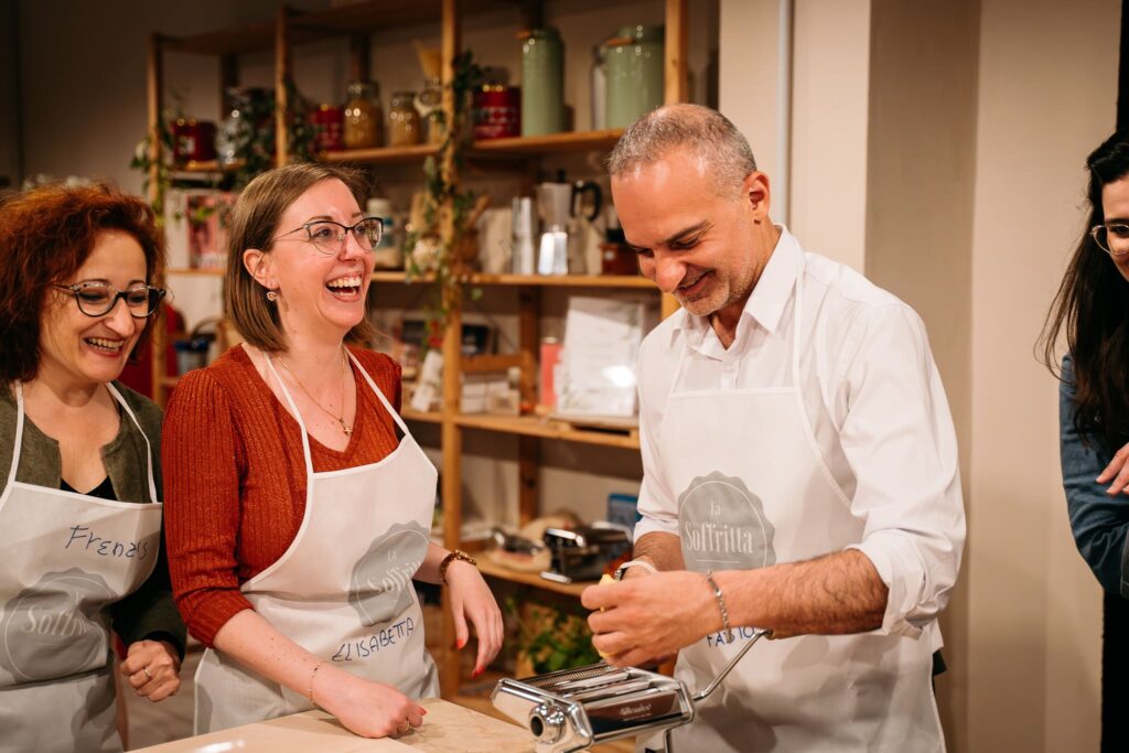 Chef mostra come stendere la pasta a due partecipanti della lezione