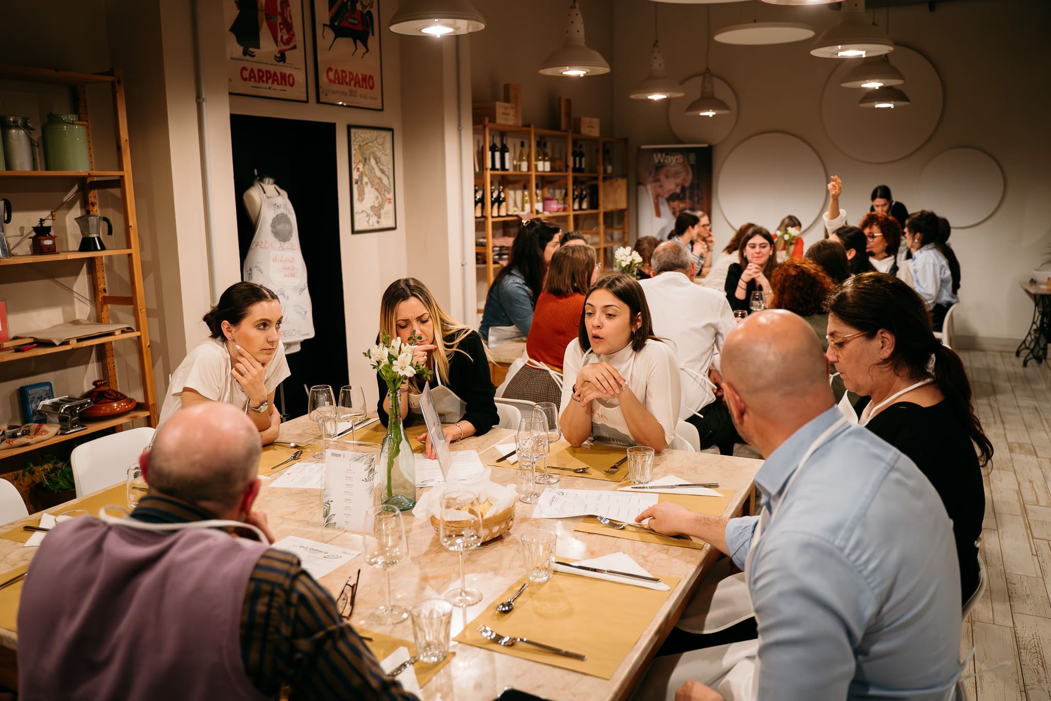 Partecipanti della lezione di cucina parlano insieme seduti a tavola