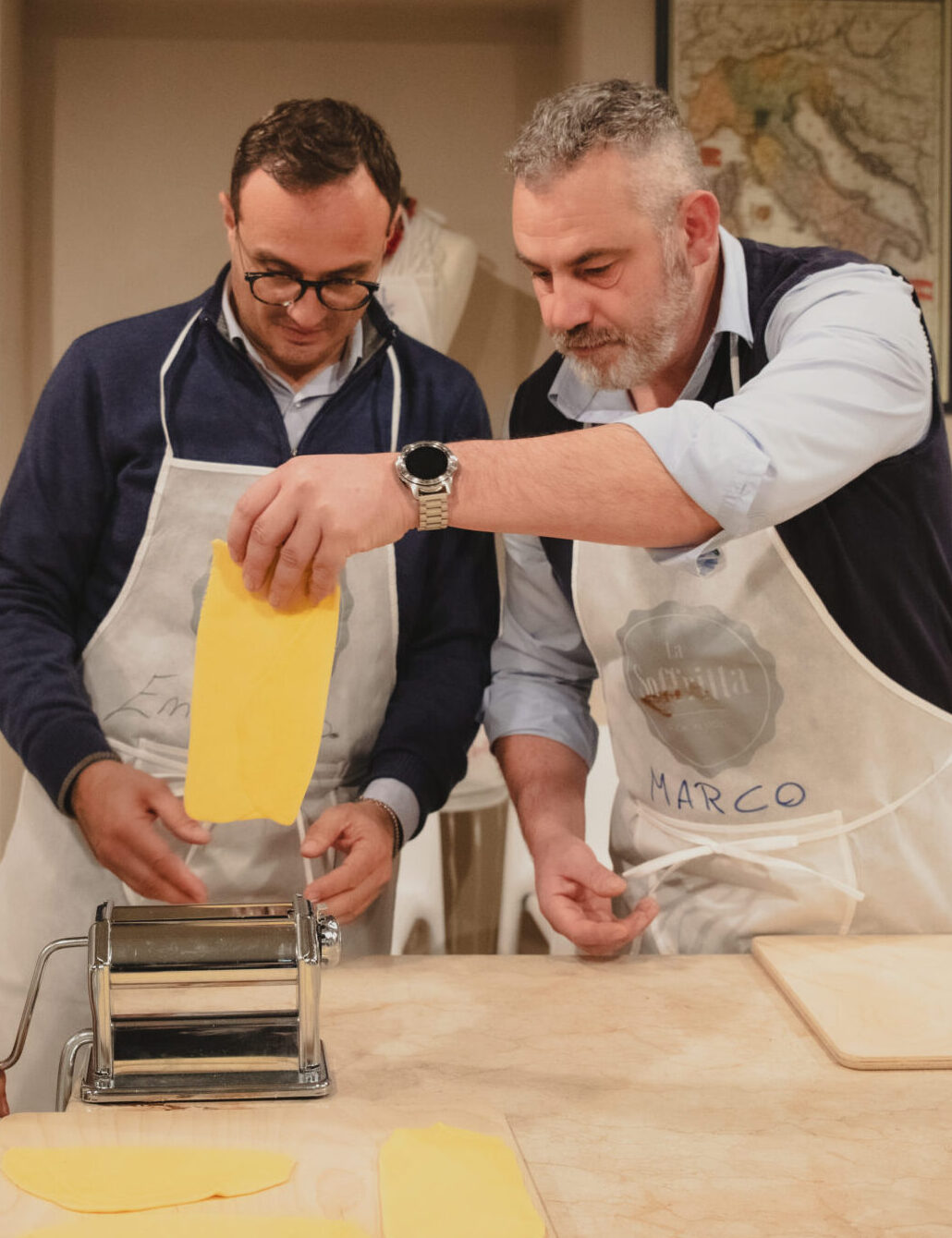 Due partecipanti stendono la pasta durante un Team Cooking de La Soffritta