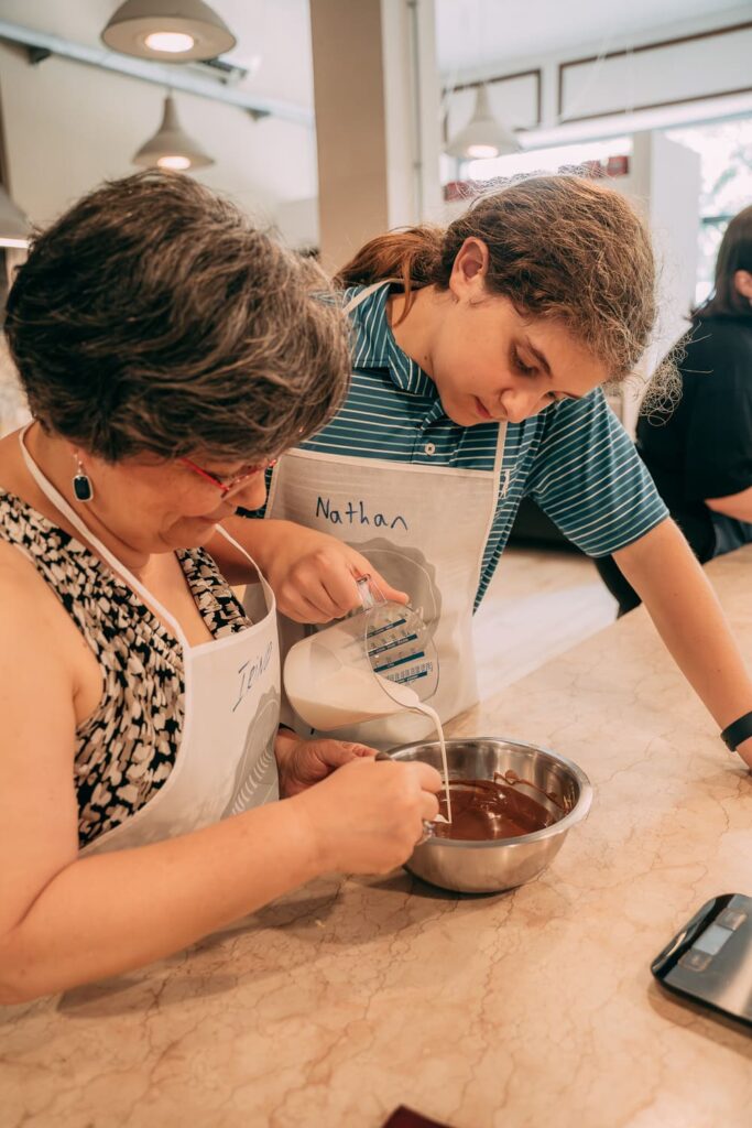 Bambina e donna versano latte in una ciotola di cioccolata durante una gelato class de La Soffritta