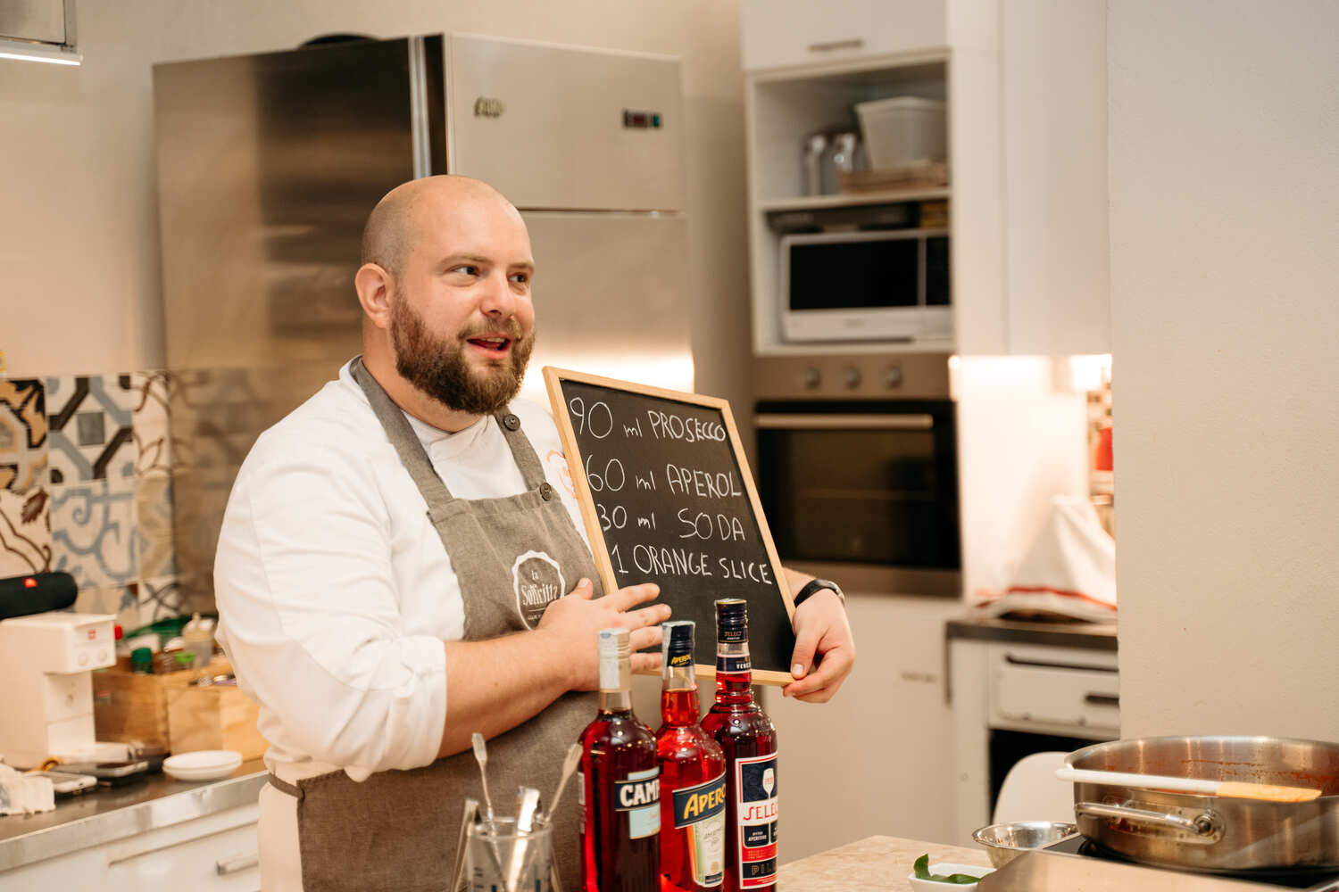 A smiling chef holding a small slate blackboard with the Spritz ingredients