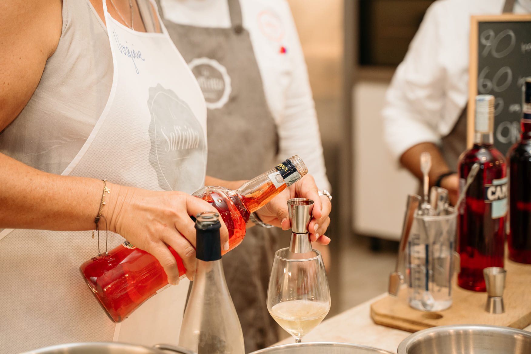 Detailed shot of a person pouring Aperol from a mixing glass into a stemmed glass
