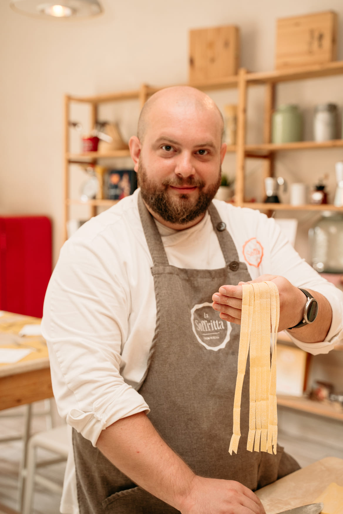 Medium shot of a chef smiling and demonstrating how to hold fresh fettuccine pasta