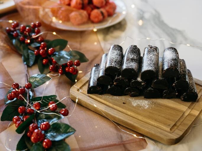 Christmas table set with sweets, chocolate rolls and decorations with red berries